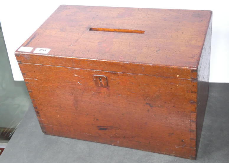 A wooden box with a rectangular slot on the top and a small latch on the front.