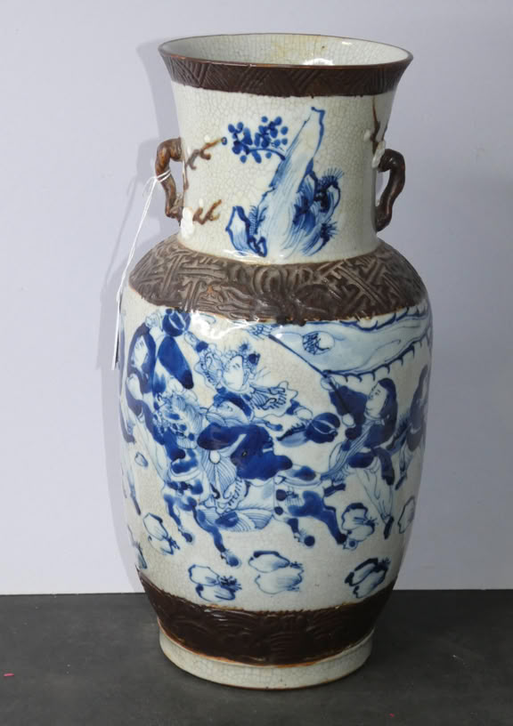 A tall ceramic vase with blue and white floral and bird designs, featuring brown accents and two small handles near the top.